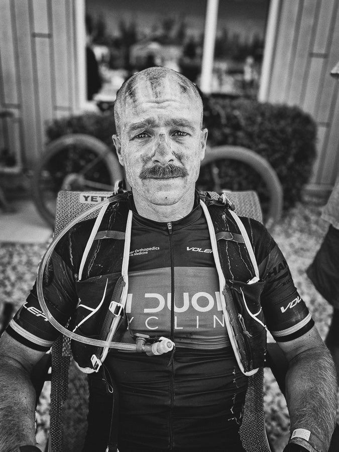 black and white photo of a bicyclist sitting with dirt on his head